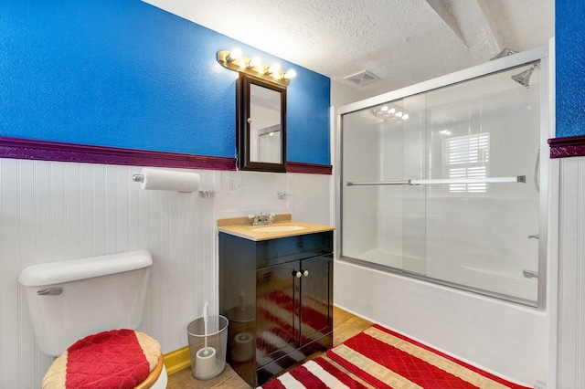 full bathroom featuring toilet, vanity, a textured ceiling, wood-type flooring, and enclosed tub / shower combo