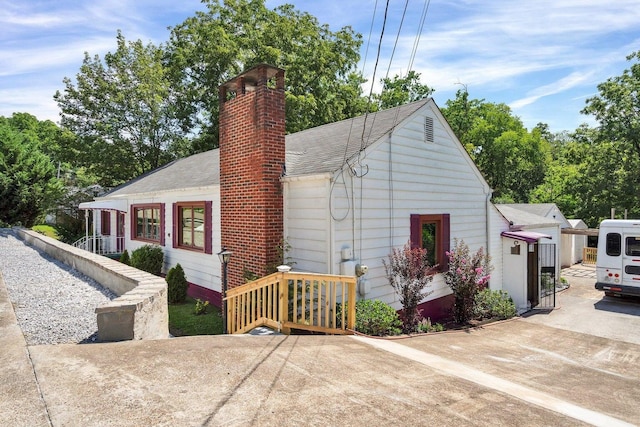 view of side of home featuring a chimney and roof with shingles