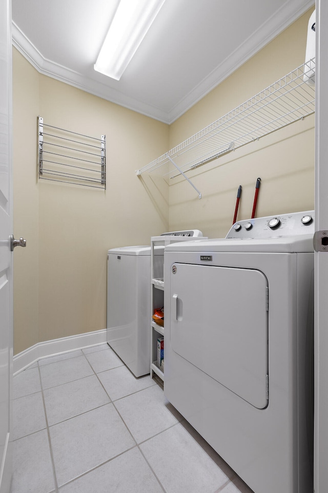 laundry area with washing machine and dryer, ornamental molding, and light tile patterned floors