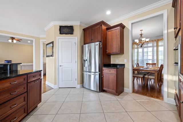 kitchen featuring ceiling fan with notable chandelier, stainless steel fridge, crown molding, and dark stone countertops