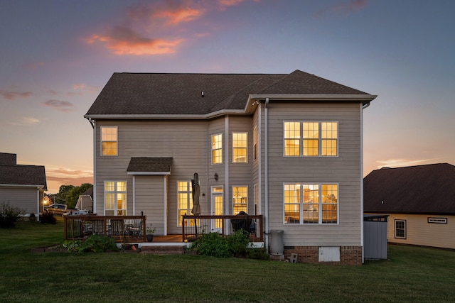 back house at dusk featuring a yard and a deck