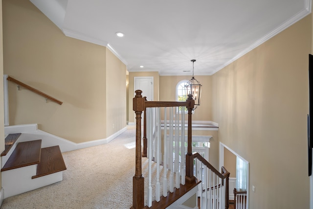 corridor with crown molding, a healthy amount of sunlight, a notable chandelier, and carpet floors