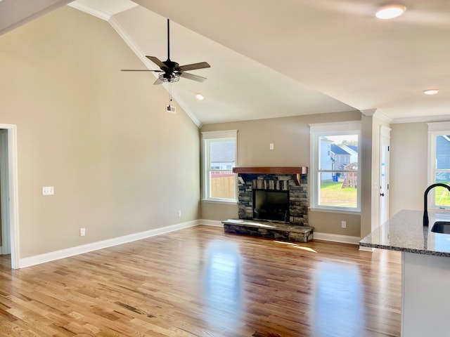 unfurnished living room featuring light hardwood / wood-style floors, sink, a fireplace, and vaulted ceiling