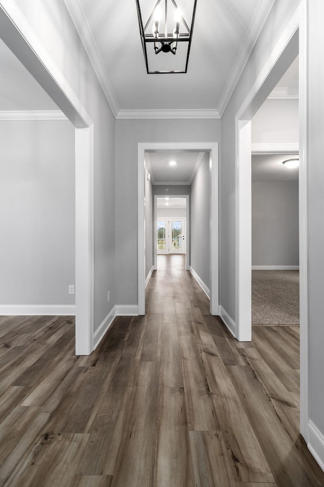 hall featuring dark wood-type flooring, crown molding, and a chandelier