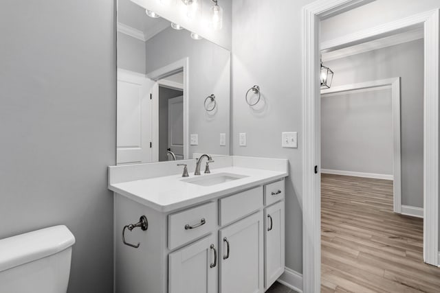 bathroom featuring vanity, toilet, crown molding, and hardwood / wood-style flooring