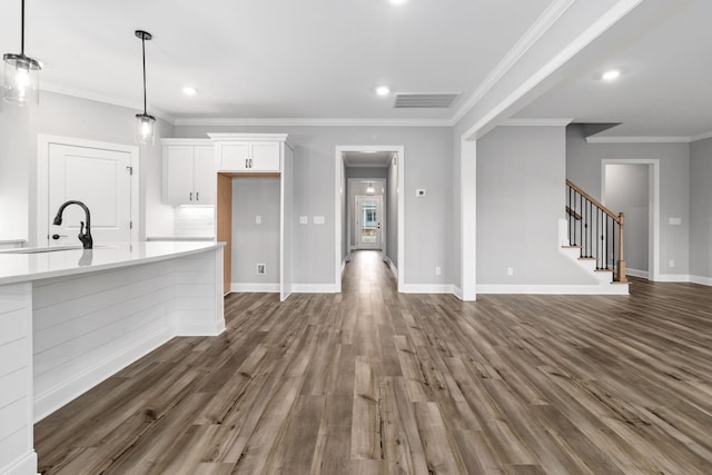 kitchen featuring white cabinets, sink, ornamental molding, pendant lighting, and dark hardwood / wood-style flooring