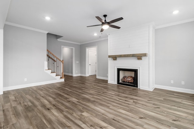 unfurnished living room with a large fireplace, hardwood / wood-style flooring, ceiling fan, and crown molding