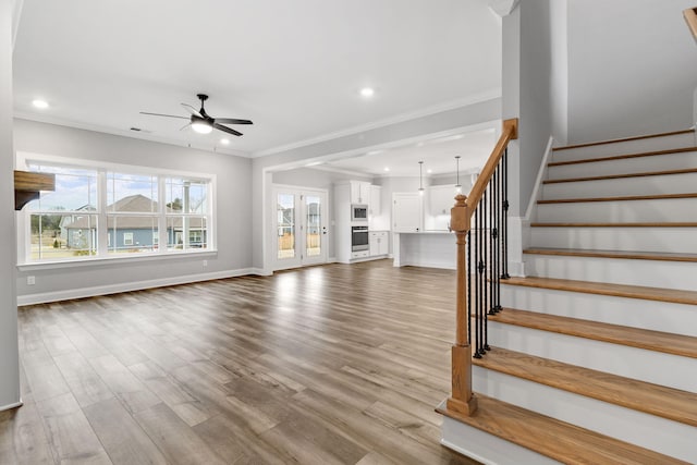 unfurnished living room with ceiling fan, crown molding, and light wood-type flooring