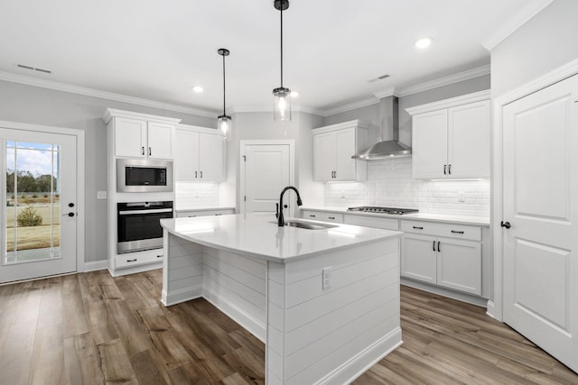 kitchen featuring hardwood / wood-style floors, white cabinets, wall chimney range hood, stainless steel appliances, and sink