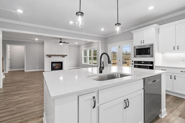 kitchen with pendant lighting, dishwasher, an island with sink, sink, and built in microwave