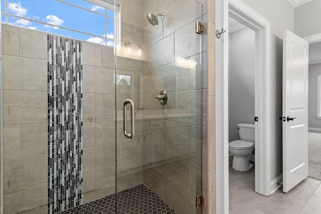 bathroom featuring toilet, ornamental molding, a shower with shower door, and tile patterned flooring