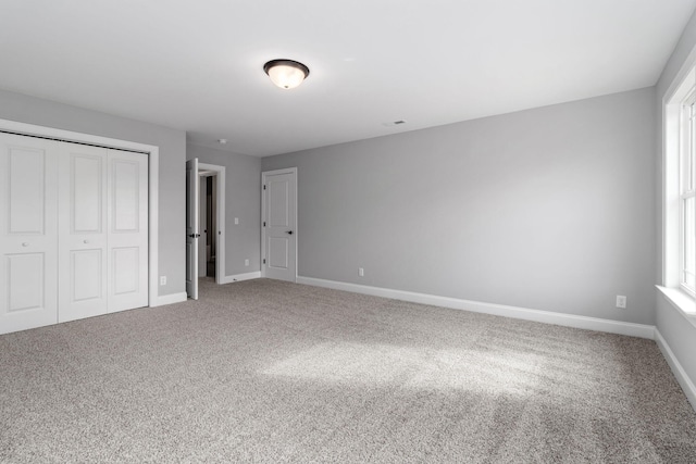 unfurnished bedroom featuring multiple windows, a closet, and carpet