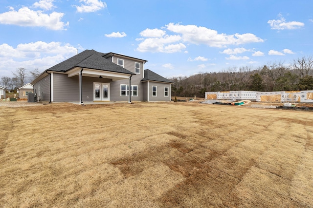 rear view of property featuring central air condition unit and a yard