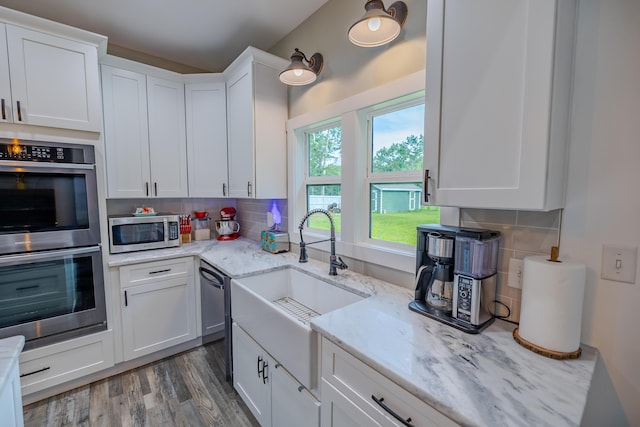kitchen featuring a sink, stainless steel appliances, backsplash, and white cabinets