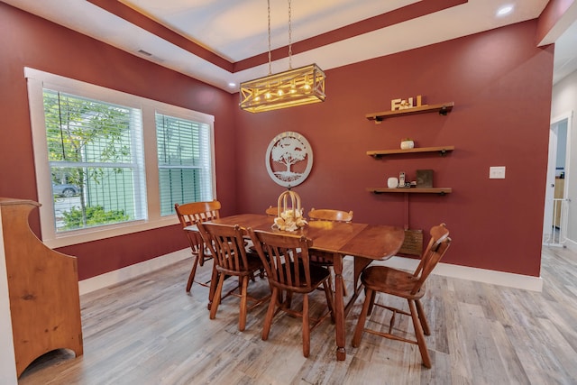 dining room featuring visible vents, a tray ceiling, light wood-style floors, baseboards, and a chandelier