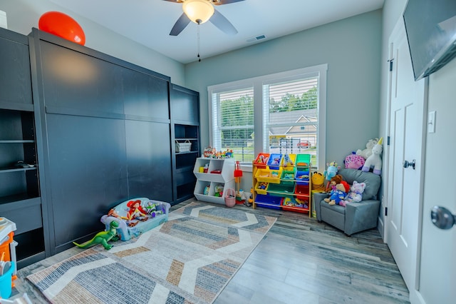 game room with a ceiling fan, wood finished floors, and visible vents