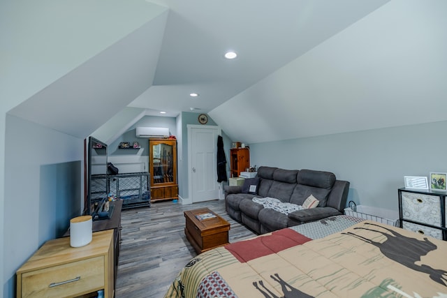 bedroom with lofted ceiling, wood-type flooring, and a wall unit AC