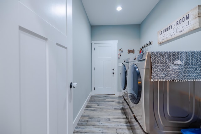 laundry area featuring washing machine and clothes dryer, laundry area, baseboards, and wood finished floors