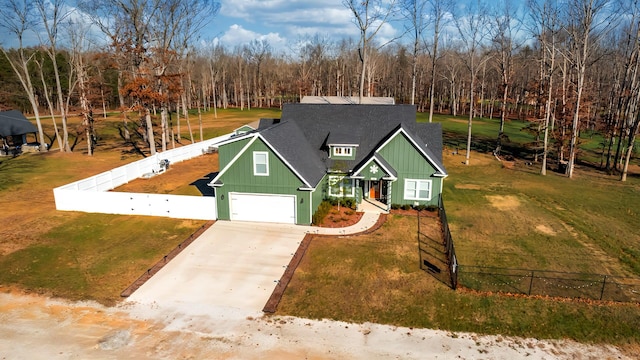 view of front of property featuring a front lawn, driveway, fence, a shingled roof, and a garage