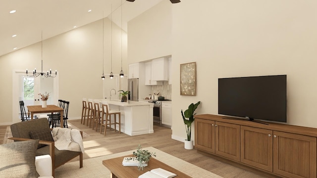 living room with high vaulted ceiling, an inviting chandelier, and light hardwood / wood-style floors