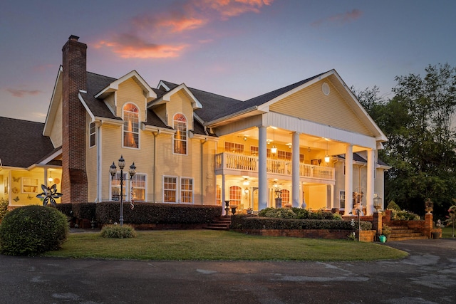 view of front of property featuring a balcony, a chimney, and a front yard