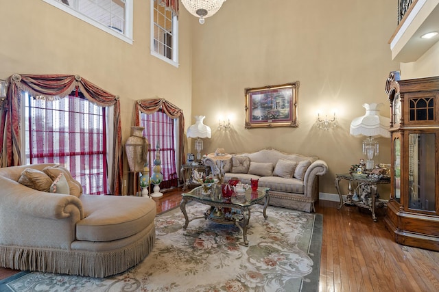 living area with hardwood / wood-style floors, baseboards, and a high ceiling