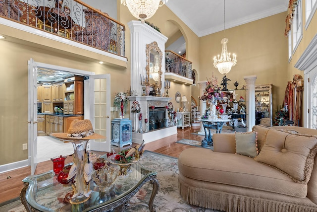 living area featuring ornamental molding, wood finished floors, an inviting chandelier, and a towering ceiling