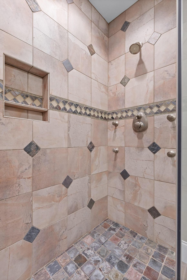 full bathroom with tiled shower and stone finish flooring