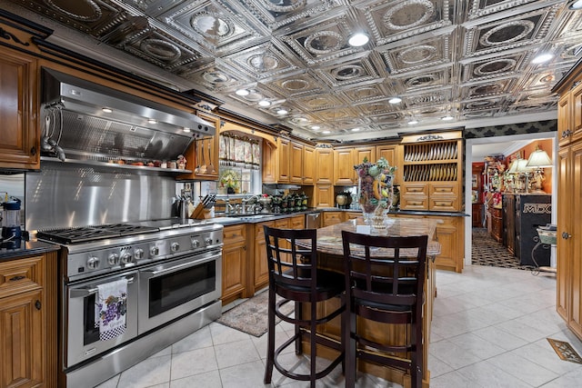 kitchen featuring wall chimney range hood, an ornate ceiling, dark countertops, and stainless steel appliances