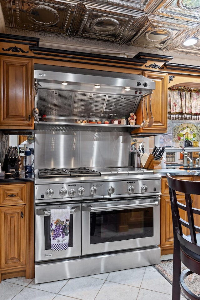 kitchen featuring light tile patterned flooring, double oven range, an ornate ceiling, and brown cabinetry