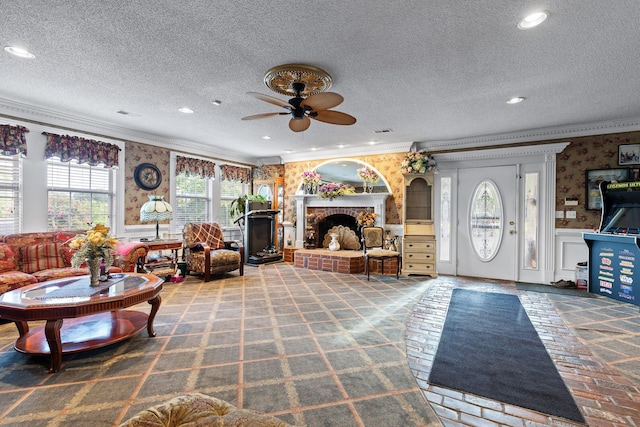 living room featuring a fireplace, ornamental molding, wallpapered walls, and a ceiling fan