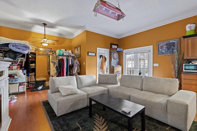 living area with a textured ceiling, ceiling fan, wood finished floors, and ornamental molding