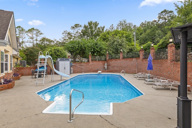 view of pool featuring a water slide, a diving board, and a patio