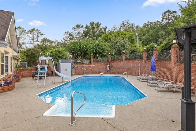 view of swimming pool featuring a fenced backyard, a fenced in pool, a water slide, and a patio