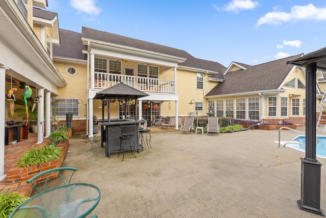 rear view of house featuring a balcony and a patio area