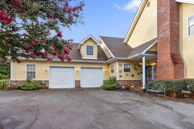 view of front of home featuring a shingled roof, brick siding, aphalt driveway, and an attached garage