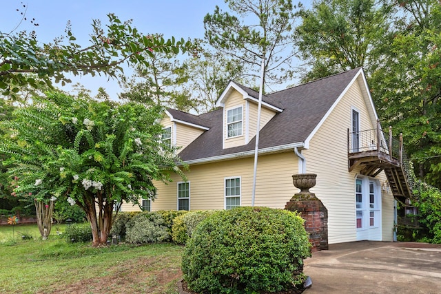 view of side of property featuring a balcony and roof with shingles