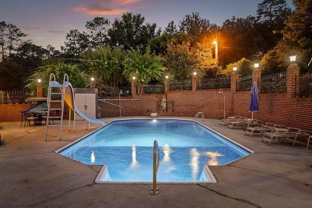 view of swimming pool with a patio, a water slide, fence, and a fenced in pool