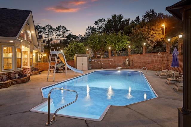 pool at dusk with a patio, fence, a fenced in pool, and a water slide