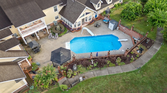 view of swimming pool with a water slide, a diving board, a storage unit, a patio, and central AC