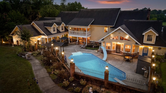 view of front of house featuring a balcony, a fenced in pool, a lawn, and a patio area