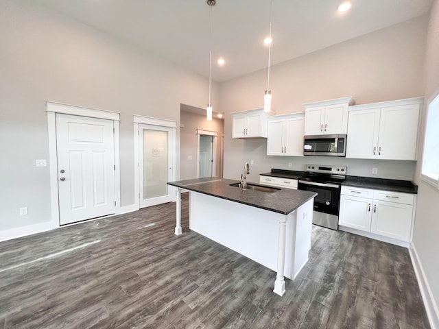 kitchen featuring appliances with stainless steel finishes, a towering ceiling, white cabinets, a kitchen island with sink, and sink