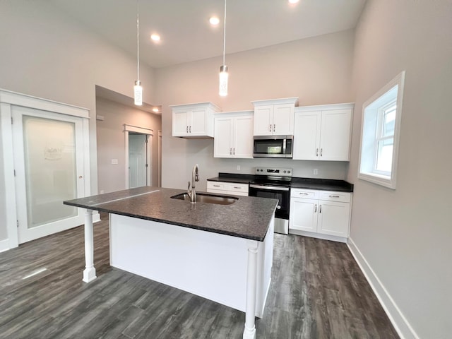 kitchen with pendant lighting, sink, a towering ceiling, a center island with sink, and appliances with stainless steel finishes