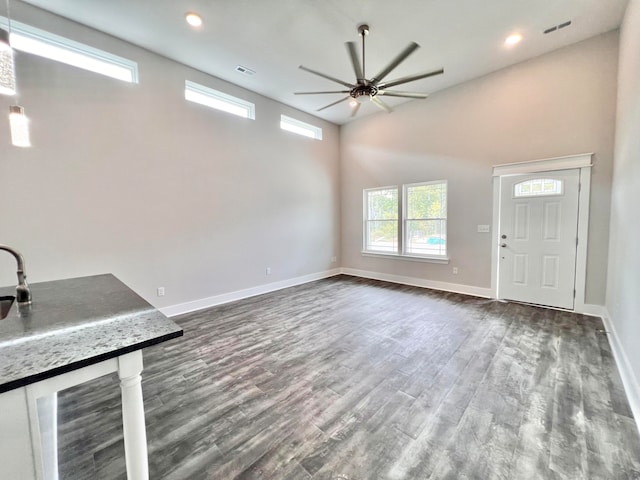 unfurnished living room with ceiling fan, dark wood-type flooring, and high vaulted ceiling