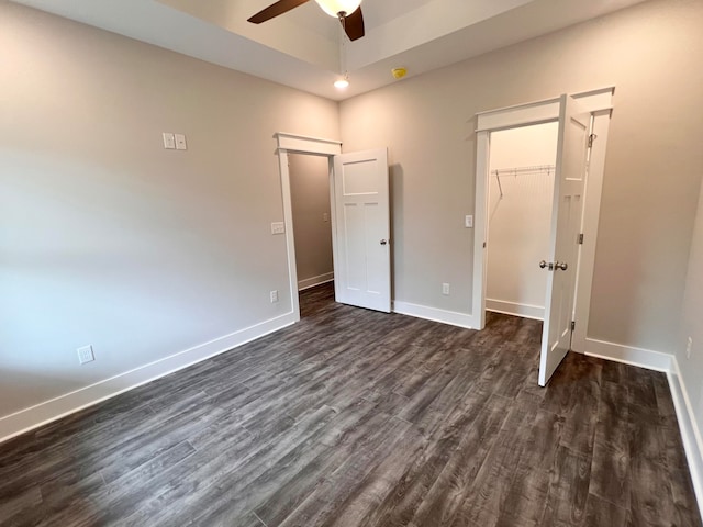 unfurnished bedroom featuring dark hardwood / wood-style flooring, ceiling fan, a walk in closet, and a closet