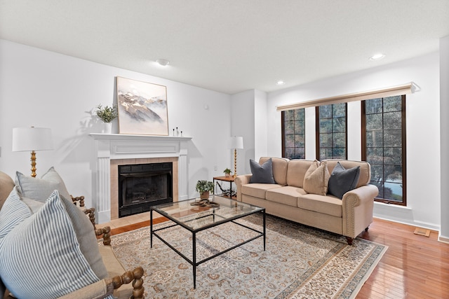 living room featuring light wood-type flooring and a tile fireplace