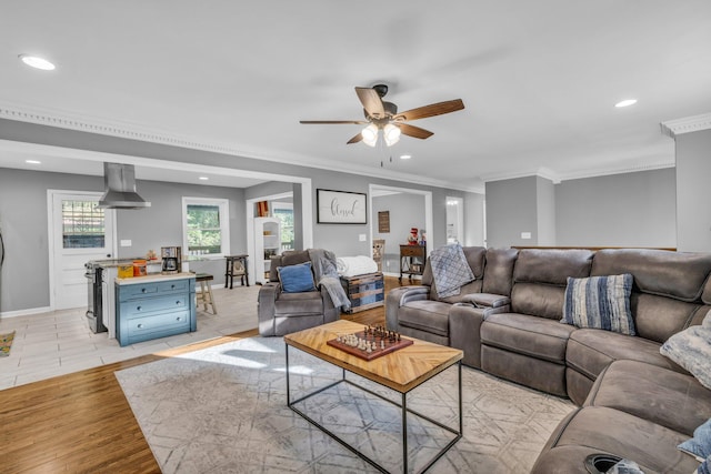 living room with light wood-type flooring, ceiling fan, and crown molding