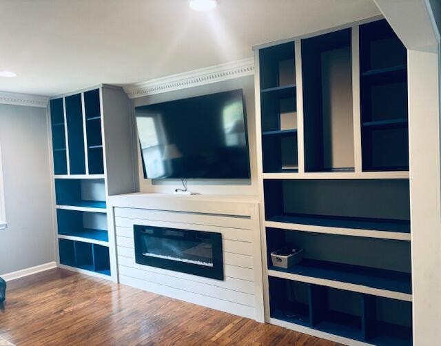 unfurnished living room featuring a glass covered fireplace and wood finished floors