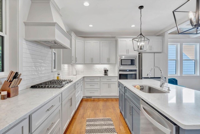 kitchen featuring custom exhaust hood, tasteful backsplash, sink, hanging light fixtures, and appliances with stainless steel finishes