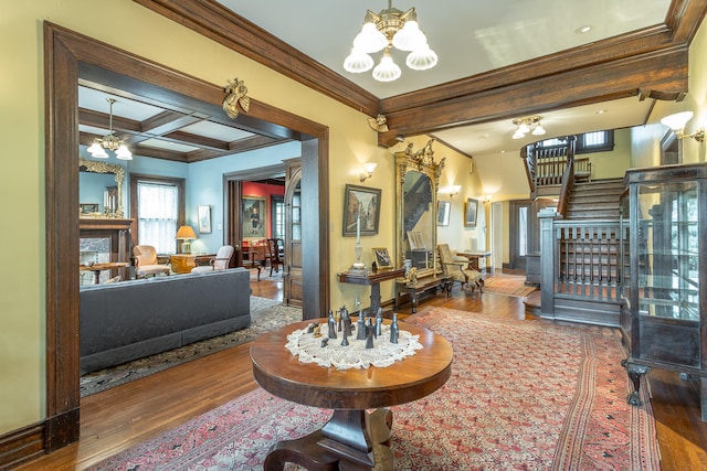 interior space with coffered ceiling, ceiling fan with notable chandelier, hardwood / wood-style floors, beam ceiling, and ornamental molding